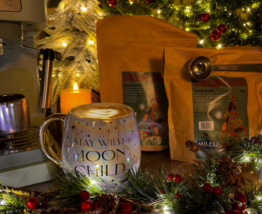 Mug filled with coffee, ground coffee/beans, and Christmas decorations.