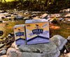 Two boxes of Miles Earl Grey tea on rocks by a stream