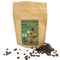 A stand-up kraft paper coffee bag labelled 'Christmas Coffee' with roasted coffee beans scattered in front on a white background.