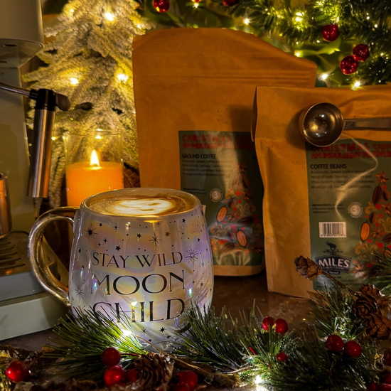 Mug filled with coffee, ground coffee/beans, and Christmas decorations.