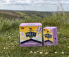 Two boxes of Miles tea on a grassy field with a scenic background