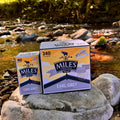 Two boxes of Miles Earl Grey tea on rocks by a stream