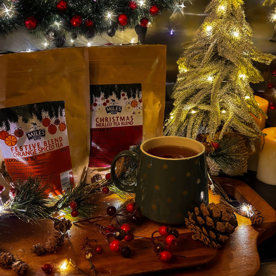 Miles Christmas tea with a mug on a wooden tray in front of a decorated Christmas tree.