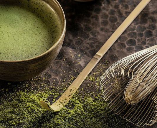 Matcha green tea bowl with whisk and spoon on a dark surface