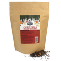 A stand-up kraft pouch of Miles Christmas Mulled Tea Blend, with a few loose tea leaves scattered in front on a white background.