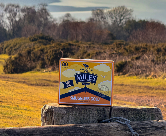 Miles Smugglers Gold tea box on a wooden post with a scenic background