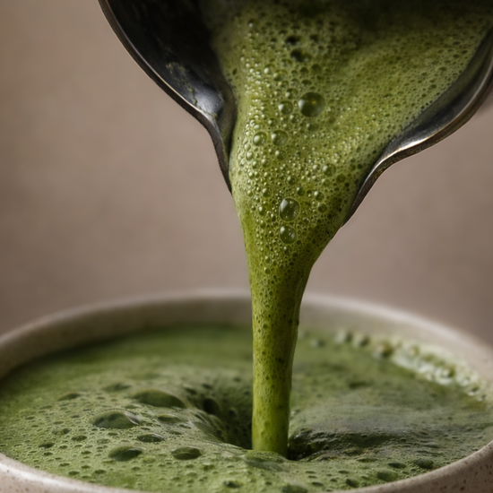 matcha being poured into a ceramic cup with a spoon.
